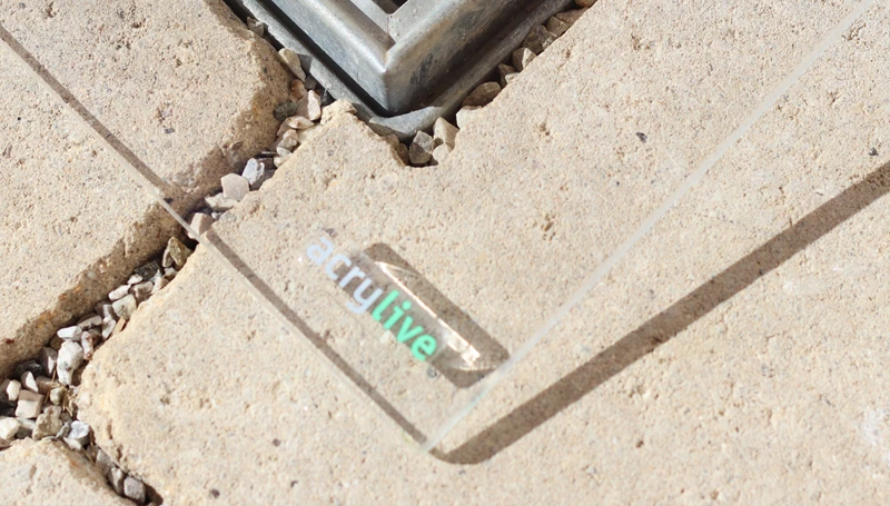 Kante einer klaren AcryS Abdeckung mit acryLive Logo auf der Betonumrandung